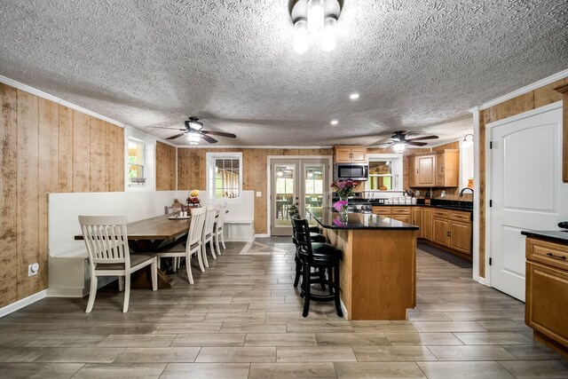 554 Hickman Shores Rd, Dover, TN 37058 - kitchen featuring ceiling fan, stainless steel microwave, ornamental molding, wood walls, and french doors
