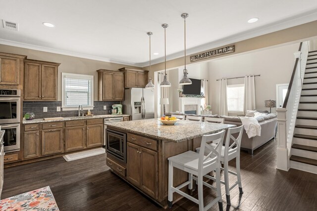 318 Finnhorse Ln, Franklin, TN 37064 - kitchen featuring stainless steel appliances, a kitchen bar, brown cabinetry, healthy amount of natural light, and crown molding
