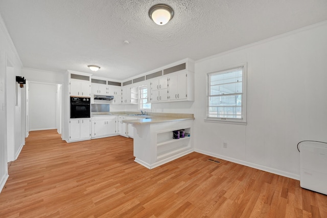 1077 Weeks Rd, Murfreesboro, TN 37127 - kitchen with oven, a peninsula, light countertops, a textured ceiling, and light wood finished floors
