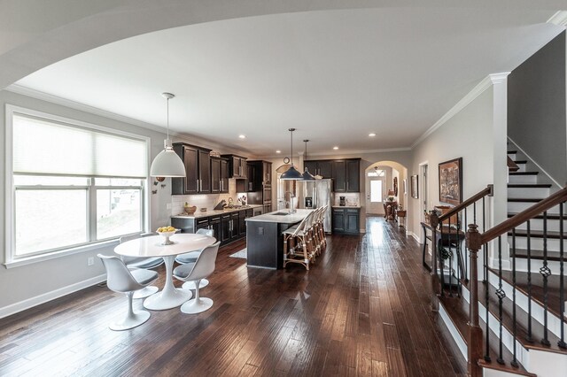 2044 Albatross Way, Gallatin, TN 37066 - kitchen with arched walkways, a center island with sink, light countertops, dark wood-style floors, and crown molding