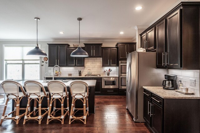 2044 Albatross Way, Gallatin, TN 37066 - kitchen featuring a kitchen bar, a kitchen island with sink, ornamental molding, stainless steel appliances, and decorative backsplash