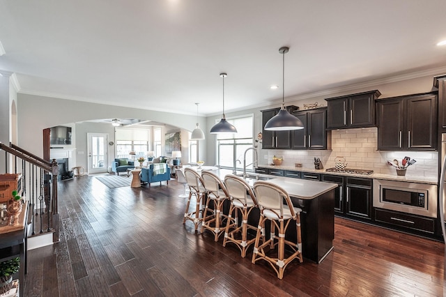 2044 Albatross Way, Gallatin, TN 37066 - kitchen featuring arched walkways, stainless steel appliances, a breakfast bar area, crown molding, and a kitchen island with sink