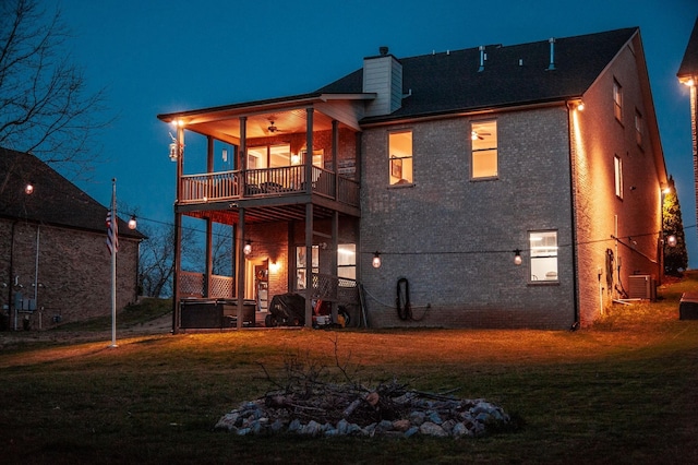 2044 Albatross Way, Gallatin, TN 37066 - back of house at night with a balcony, a yard, a chimney, and brick siding