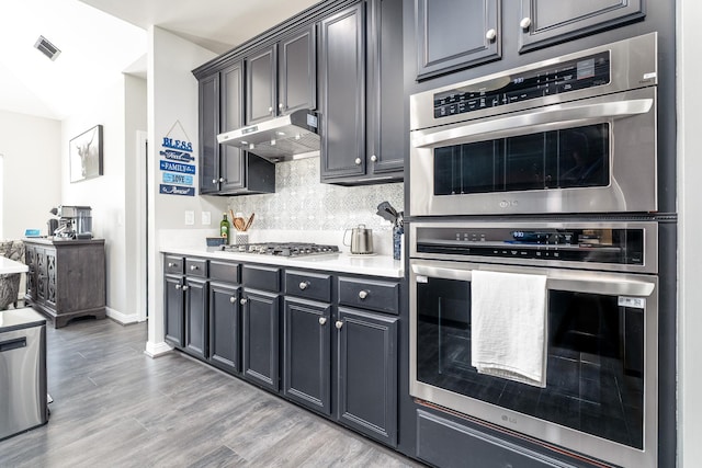 3134 Friars Bridge Pass, Franklin, TN 37064 - kitchen with ventilation hood, tasteful backsplash, light countertops, stainless steel appliances, and light wood finished floors