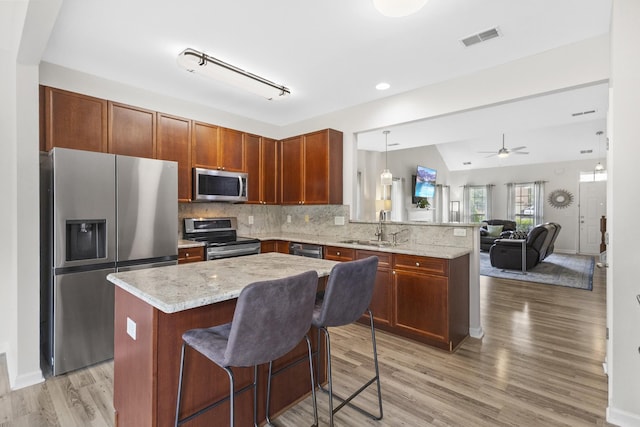 2003 Solomon Ct, Spring Hill, TN 37174 - kitchen featuring stainless steel appliances, a peninsula, light wood-type flooring, tasteful backsplash, and open floor plan