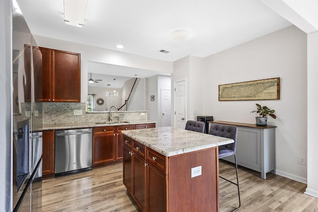 2003 Solomon Ct, Spring Hill, TN 37174 - kitchen featuring stainless steel appliances, a kitchen breakfast bar, light wood-type flooring, decorative backsplash, and light stone counters