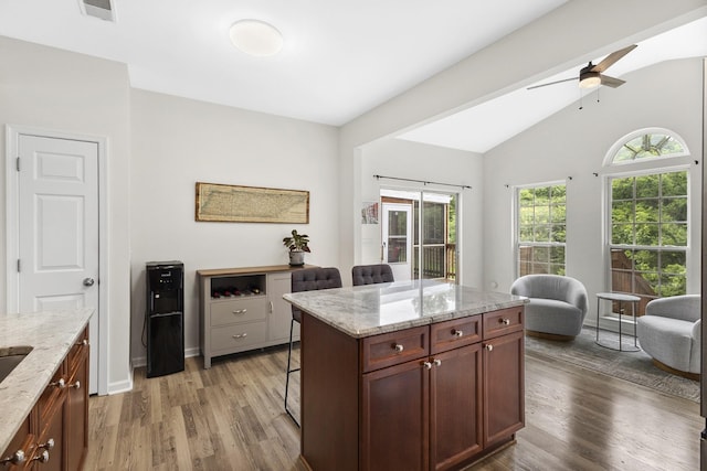 2003 Solomon Ct, Spring Hill, TN 37174 - kitchen with vaulted ceiling, a kitchen breakfast bar, wood finished floors, ceiling fan, and light stone counters