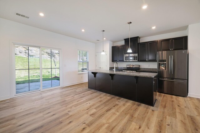 4316 Summercrest Blvd Unit 713, Antioch, TN 37013 - kitchen with appliances with stainless steel finishes, a kitchen bar, light wood-style floors, a center island with sink, and light stone counters