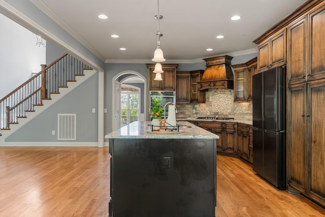429 Acacia Grove Ln, Lebanon, TN 37087 - kitchen with appliances with stainless steel finishes, custom exhaust hood, light wood-type flooring, arched walkways, and crown molding
