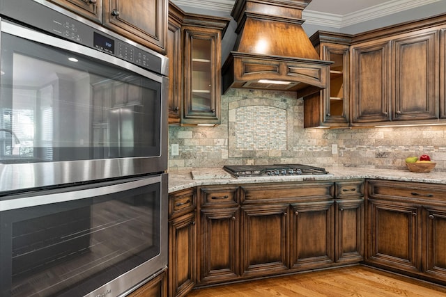 429 Acacia Grove Ln, Lebanon, TN 37087 - kitchen featuring appliances with stainless steel finishes, premium range hood, light stone counters, crown molding, and backsplash