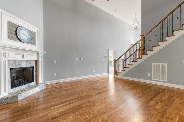 429 Acacia Grove Ln, Lebanon, TN 37087 - unfurnished living room featuring a high ceiling, stairs, a premium fireplace, crown molding, and light wood-style floors