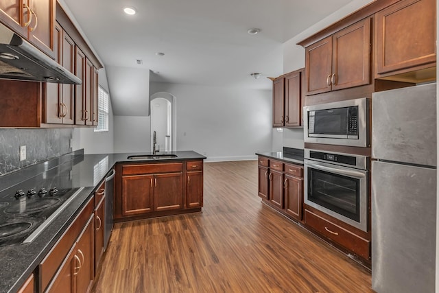 240 Sounder Cir, La Vergne, TN 37086 - kitchen with appliances with stainless steel finishes, dark wood finished floors, under cabinet range hood, arched walkways, and a peninsula