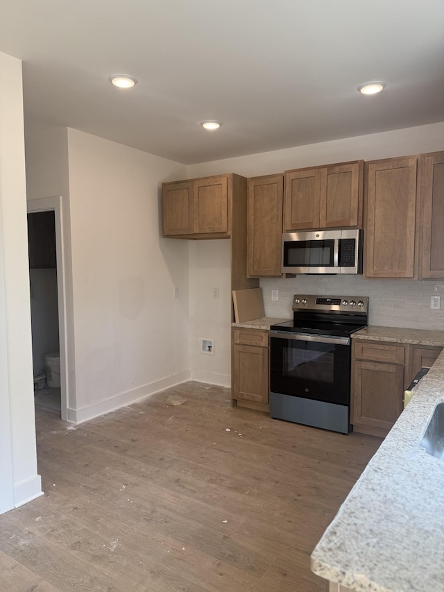 321 Wesson Dr, Clarksville, TN 37043 - kitchen with appliances with stainless steel finishes, light wood-style flooring, brown cabinets, decorative backsplash, and recessed lighting