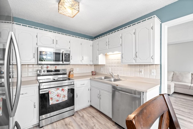 919 Desota Ln, Oak Grove, KY 42262 - kitchen with stainless steel appliances, light wood-type flooring, backsplash, a textured ceiling, and light countertops
