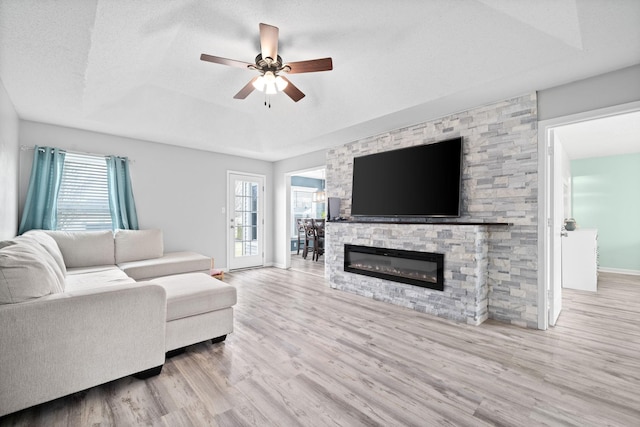 919 Desota Ln, Oak Grove, KY 42262 - living area with wood finished floors, a ceiling fan, a tray ceiling, and a stone fireplace