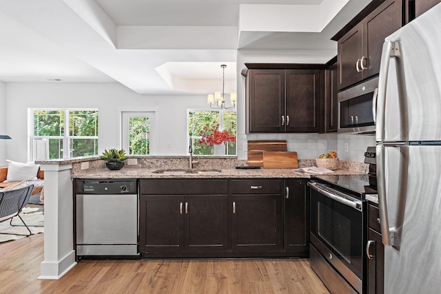 1108 Somerset Springs Dr, Spring Hill, TN 37174 - kitchen featuring stainless steel appliances, a peninsula, light wood-style flooring, backsplash, and light stone counters