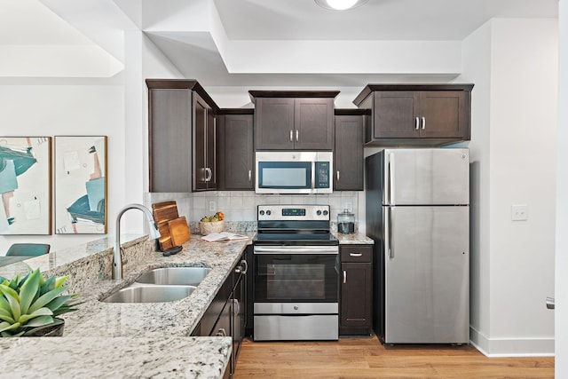 1108 Somerset Springs Dr, Spring Hill, TN 37174 - kitchen with appliances with stainless steel finishes, dark brown cabinets, light stone counters, light wood-style flooring, and tasteful backsplash