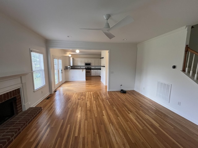 2010 Katach Ct, Spring Hill, TN 37174 - unfurnished living room with light wood-style floors, a ceiling fan, a brick fireplace, crown molding, and stairway
