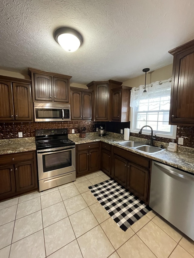 532 Douglas Ln, Lafayette, TN 37083 - kitchen with appliances with stainless steel finishes, backsplash, light tile patterned floors, dark brown cabinetry, and pendant lighting