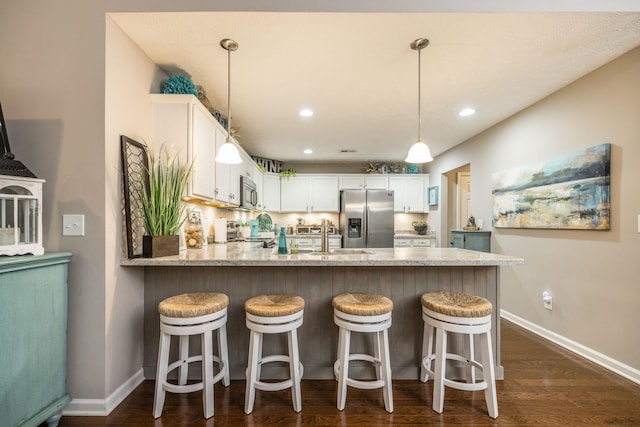 395 Devon Chase Hl Unit 3002, Gallatin, TN 37066 - kitchen with appliances with stainless steel finishes, a peninsula, white cabinets, light stone countertops, and dark wood-style flooring