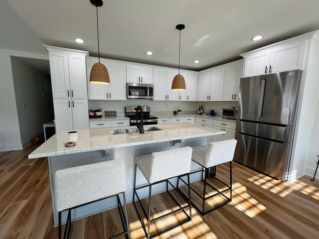 543 2nd Ave N, Lewisburg, TN 37091 - kitchen featuring appliances with stainless steel finishes, white cabinets, dark wood finished floors, an island with sink, and decorative light fixtures