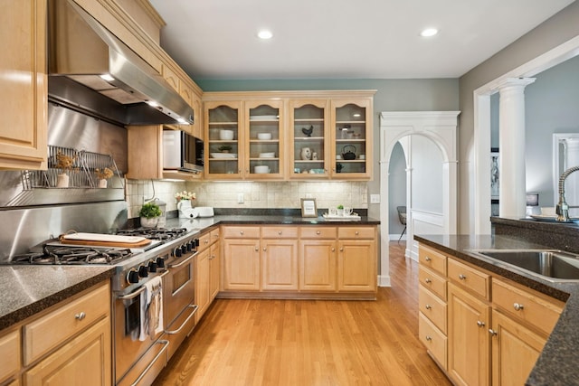 1387 Floyd Rd, Eagleville, TN 37060 - kitchen featuring double oven range, wall chimney range hood, light wood-style flooring, light brown cabinets, and glass insert cabinets