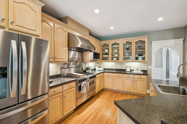 1387 Floyd Rd, Eagleville, TN 37060 - kitchen with stainless steel appliances, wall chimney exhaust hood, light brown cabinets, light wood-style floors, and dark countertops