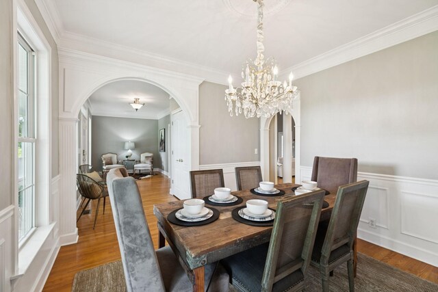 1387 Floyd Rd, Eagleville, TN 37060 - dining space featuring arched walkways, a chandelier, wood finished floors, ornamental molding, and a wainscoted wall