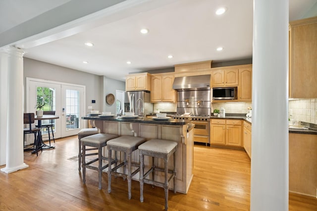 1387 Floyd Rd, Eagleville, TN 37060 - kitchen with ornate columns, stainless steel appliances, light brown cabinets, wall chimney exhaust hood, and recessed lighting