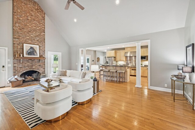 1387 Floyd Rd, Eagleville, TN 37060 - living area featuring high vaulted ceiling, a ceiling fan, light wood-style floors, a fireplace, and decorative columns