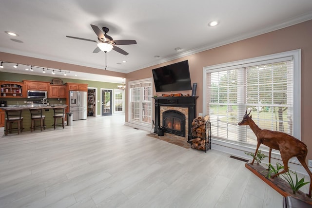 118 Stonebridge, Selmer, TN 38375 - living room featuring a fireplace with flush hearth, ceiling fan, crown molding, light wood finished floors, and a chandelier