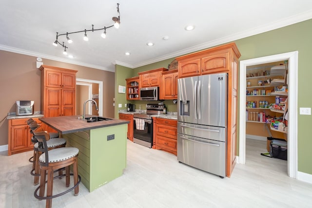 118 Stonebridge, Selmer, TN 38375 - kitchen with appliances with stainless steel finishes, ornamental molding, a kitchen island with sink, brown cabinets, and recessed lighting