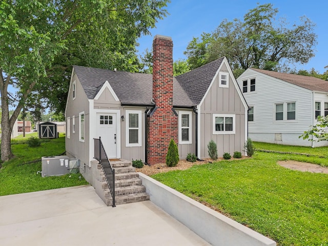 410 Campbell Ave, Tullahoma, TN 37388 - view of front of home featuring board and batten siding, roof with shingles, a chimney, and a front lawn