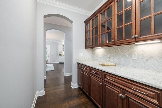 6826 Falls Ridge Ln, College Grove, TN 37046 - kitchen with arched walkways, ornamental molding, tasteful backsplash, dark wood-style floors, and light stone counters