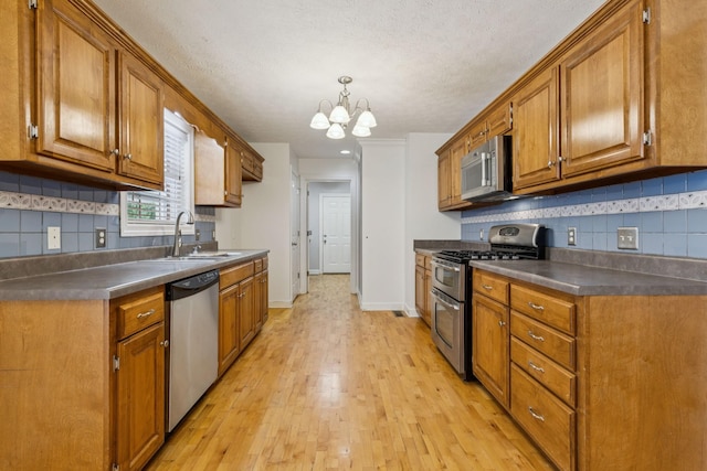 209 Taylor Creek Ln, Chapel Hill, TN 37034 - kitchen featuring appliances with stainless steel finishes, brown cabinets, light wood-style flooring, a chandelier, and a textured ceiling