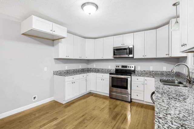 458 Robins Trl, Westmoreland, TN 37186 - kitchen featuring stainless steel appliances, light stone counters, light wood finished floors, white cabinets, and a textured ceiling