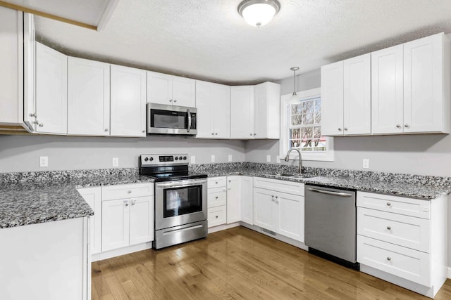 458 Robins Trl, Westmoreland, TN 37186 - kitchen featuring appliances with stainless steel finishes, dark stone countertops, wood finished floors, and a textured ceiling