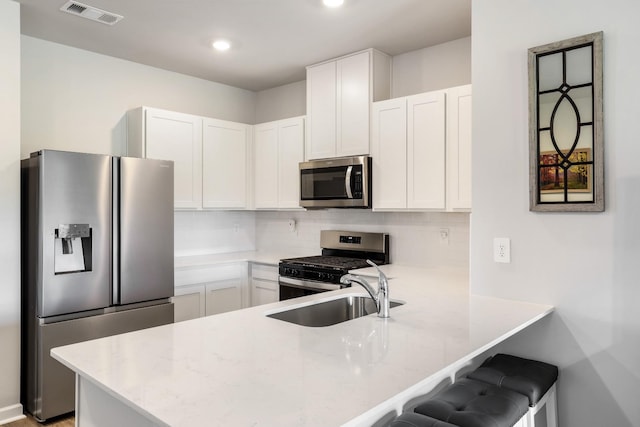 7178 Lang Ave, White House, TN 37188 - kitchen featuring appliances with stainless steel finishes, a peninsula, tasteful backsplash, white cabinetry, and recessed lighting