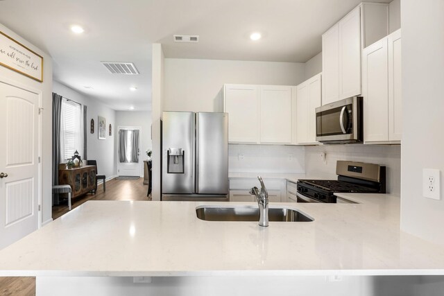 7178 Lang Ave, White House, TN 37188 - kitchen with stainless steel appliances, light stone counters, decorative backsplash, white cabinets, and recessed lighting