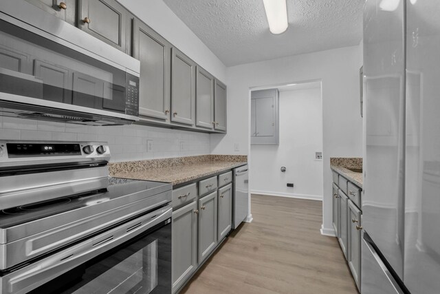 308 Custer Ct, Smyrna, TN 37167 - kitchen with stainless steel appliances, gray cabinets, backsplash, light wood-type flooring, and a textured ceiling