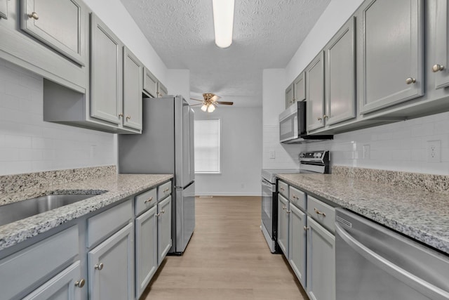 308 Custer Ct, Smyrna, TN 37167 - kitchen with stainless steel appliances, ceiling fan, gray cabinets, backsplash, and a textured ceiling