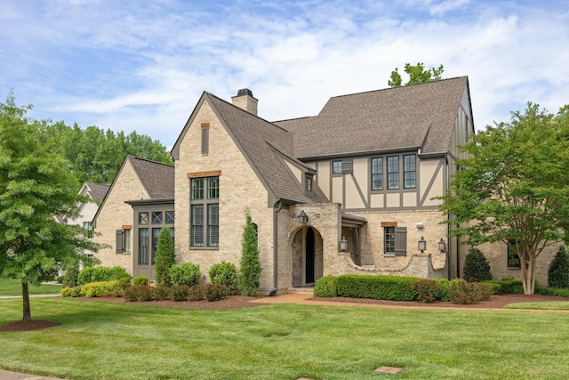 4310 Kings Camp Ct, Arrington, TN 37014 - tudor house featuring roof with shingles, a chimney, a front lawn, and brick siding