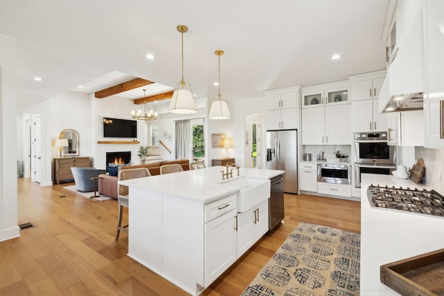 973 Hall Cemetery Rd, Burns, TN 37029 - kitchen with stainless steel appliances, recessed lighting, a large fireplace, light wood-style flooring, and white cabinets