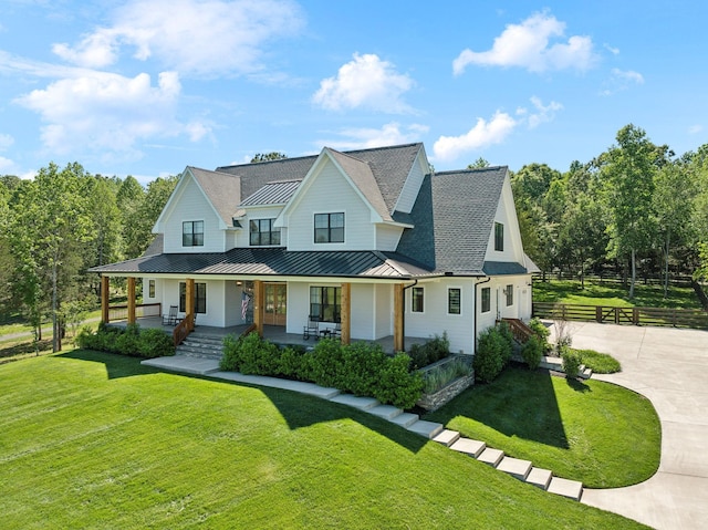 973 Hall Cemetery Rd, Burns, TN 37029 - modern farmhouse style home featuring a standing seam roof, concrete driveway, a porch, a metal roof, and a shingled roof