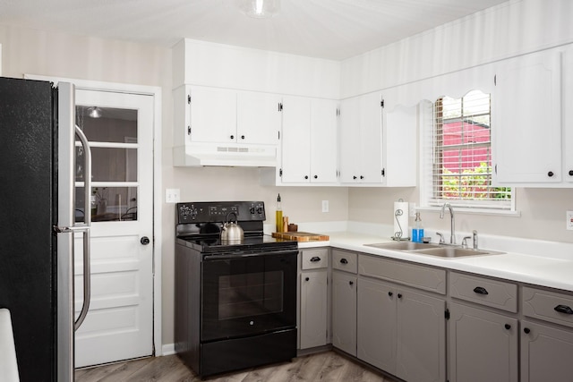 1808 Nassau Blvd, Florence, AL 35630 - kitchen featuring black electric range, freestanding refrigerator, under cabinet range hood, gray cabinetry, and light wood-type flooring