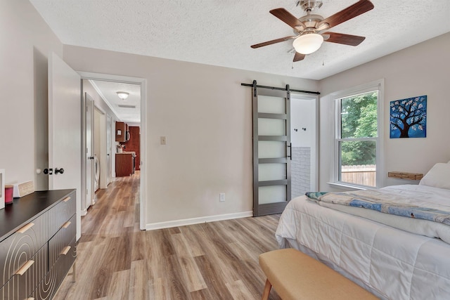 141 Springbrook Pl, Joelton, TN 37080 - bedroom with light wood finished floors, a barn door, a textured ceiling, and a ceiling fan