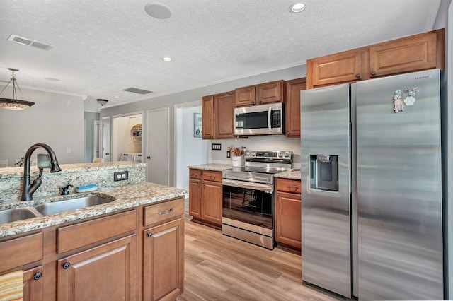 141 Springbrook Pl, Joelton, TN 37080 - kitchen with appliances with stainless steel finishes, light wood finished floors, brown cabinets, light stone countertops, and a textured ceiling
