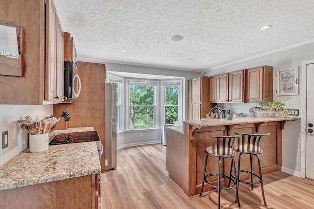 141 Springbrook Pl, Joelton, TN 37080 - kitchen with stainless steel appliances, a breakfast bar, a peninsula, a textured ceiling, and brown cabinets