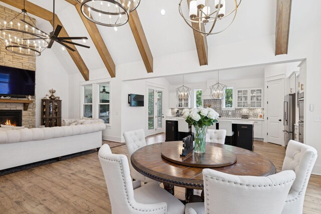 5128 Terravista Ln, Franklin, TN 37064 - dining area with a chandelier, beamed ceiling, light wood-style floors, a fireplace, and high vaulted ceiling