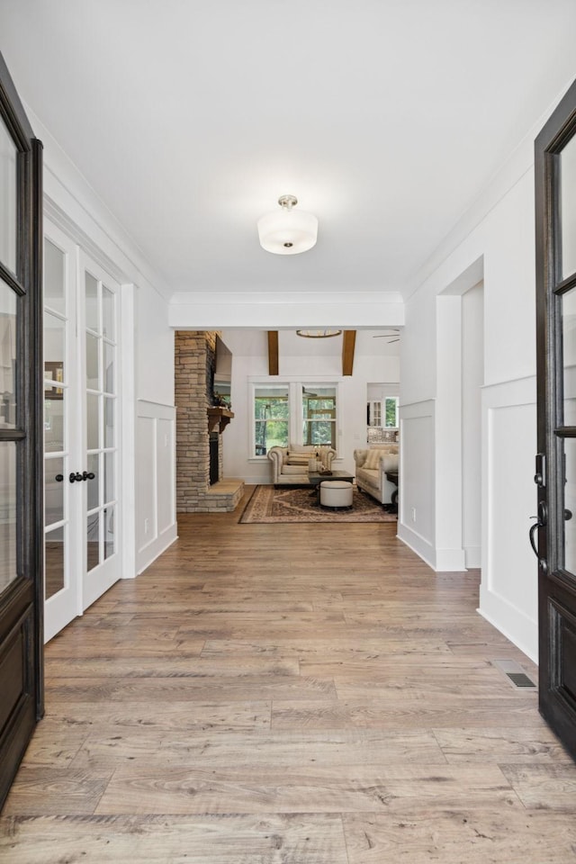 5128 Terravista Ln, Franklin, TN 37064 - entryway with french doors, ornamental molding, light wood finished floors, a decorative wall, and a stone fireplace